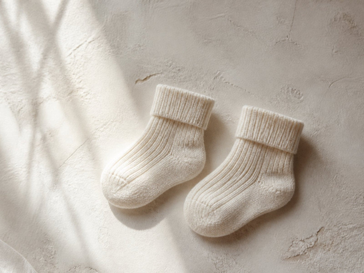 A pair of ribbed organic cotton baby socks on off-white plaster